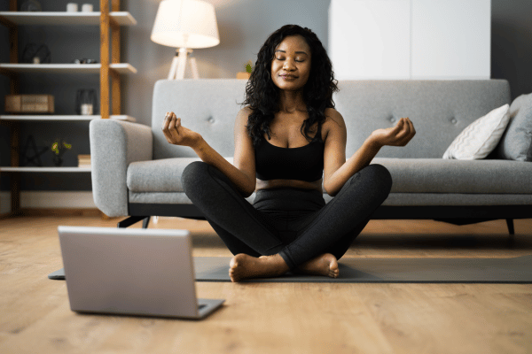 Vrouw op yogamat thuis voor laptop tijdens online Do-In Yoga les