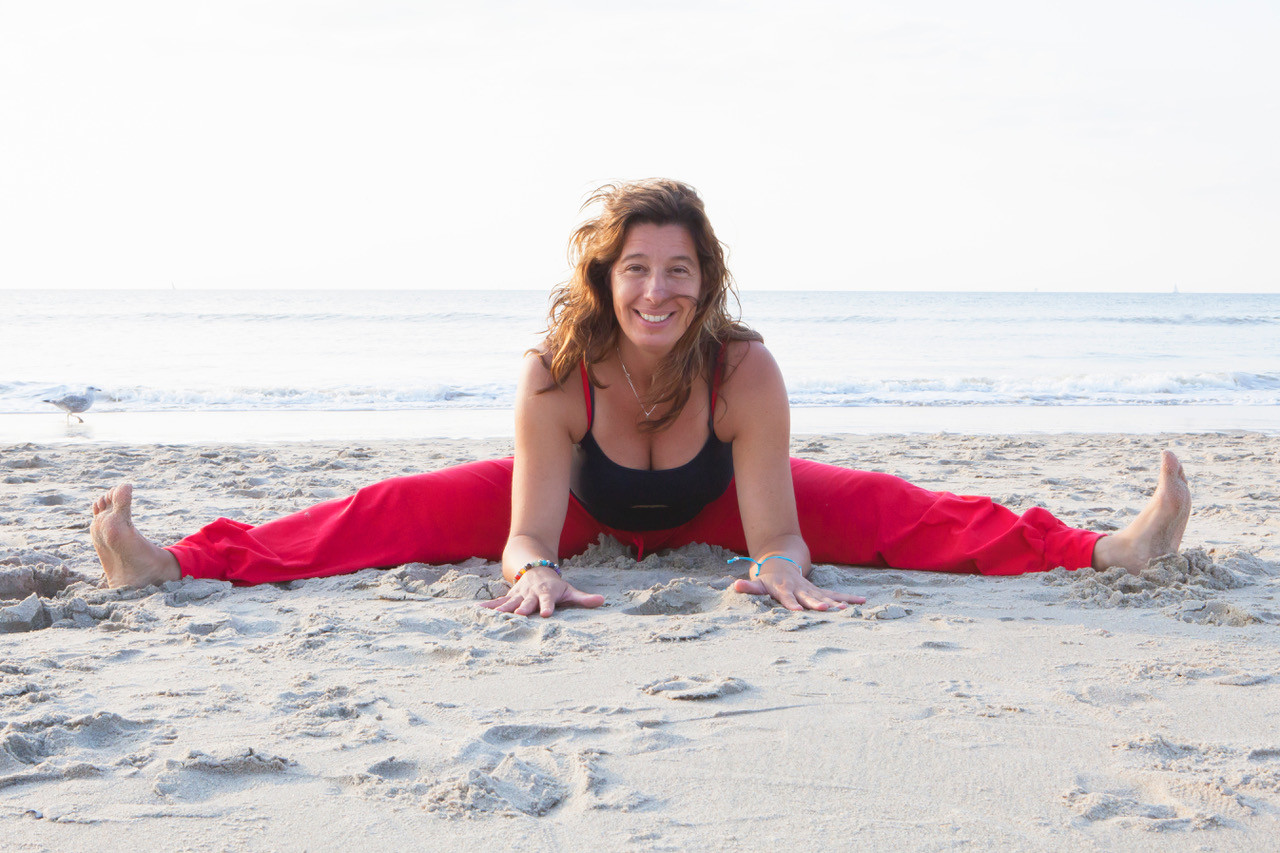 Claudia Heijdel op het strand in spreidzit met handen in het midden op de grond
