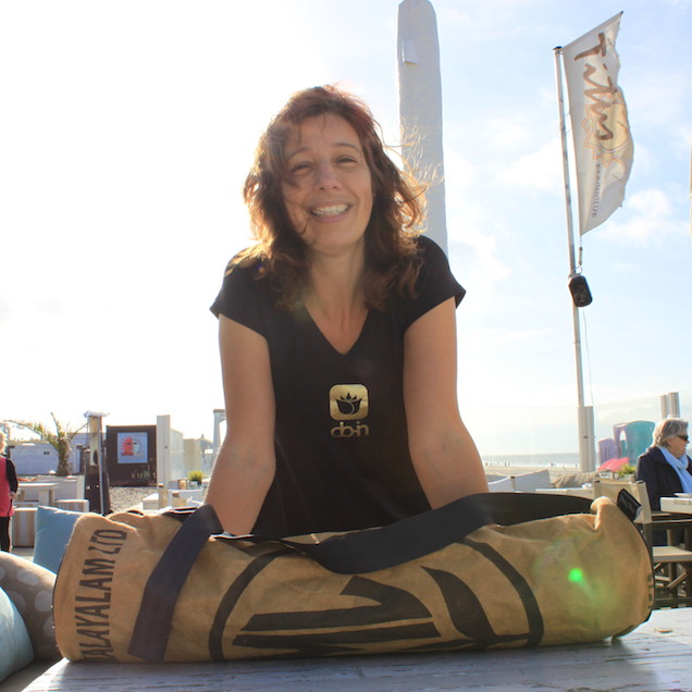 Claudia Heijdel in Do-In Yogakleding bij strandtent met yogamat